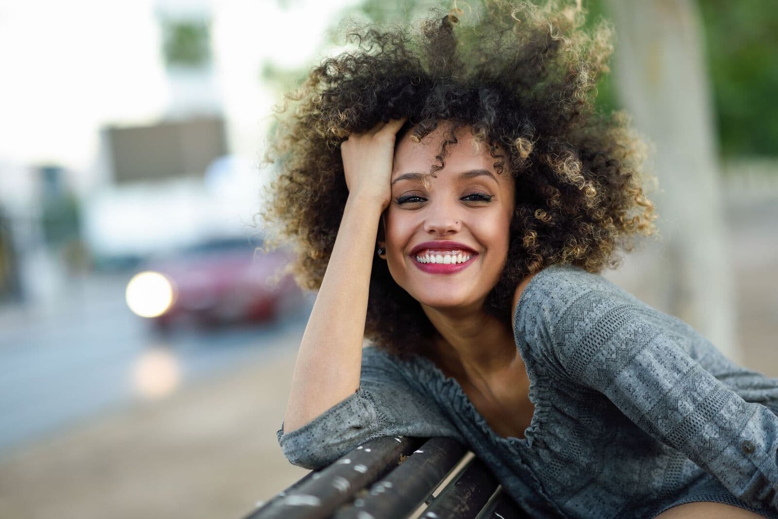 A smiling person resting on a bench on a city street