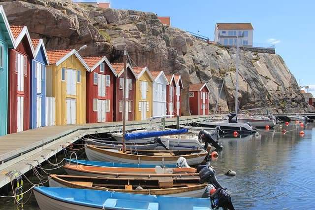 Brightly painted wooden boathouses and small boats along a harbour