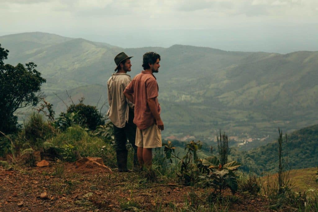 Two people looking out over a green valley from a hilltop