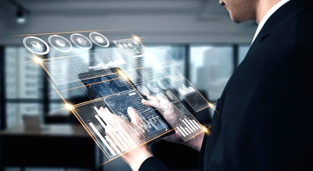 A person in a suit touching a composited holographic dashboard above a tablet
