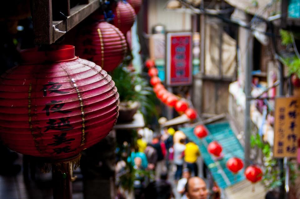 Red paper lanterns strung above a narrow street market